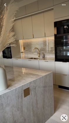 a modern kitchen with marble counter tops and white cabinets, along with an island in the middle