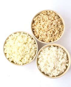 three bowls filled with rice on top of a white table