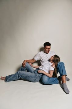 a man and woman sitting on the ground with their arms around each other as they cuddle