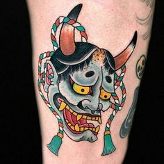 a tattoo on the leg of a man with an evil mask and horns in his hair