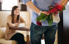 a man is holding flowers in his hand while a woman sits on the couch behind him