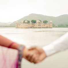 two people are holding hands near the water