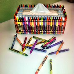 crayons are lined up on a table next to a tissue dispenser