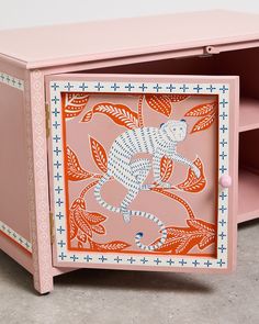 a pink cabinet with an orange and white design on the front, painted like a monkey