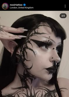 a woman with black and white makeup has her face painted to look like a tree