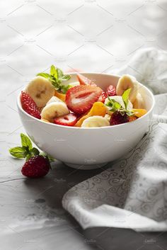 a white bowl filled with sliced fruit on top of a table next to a napkin