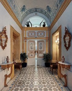 an ornately decorated hallway leads to another room with mirrors and vases on the wall