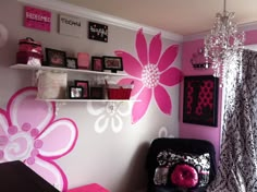 a pink and white room with flowers painted on the wall, black chair, and chandelier