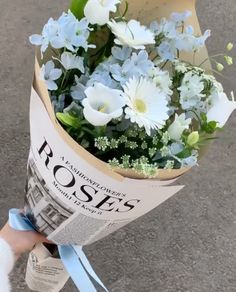 a person holding a bouquet of flowers in their hand with newspaper paper wrapped around it