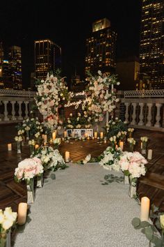 an outdoor ceremony setup with candles and flowers on the ground in front of tall buildings