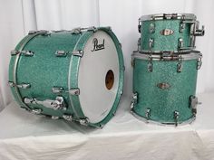 two green glittered drums sitting next to each other on a white tablecloth covered surface