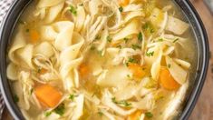 a bowl filled with chicken noodle soup on top of a wooden table