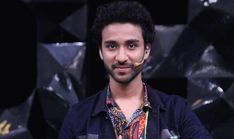 a man with a nose ring standing in front of a black background and looking at the camera