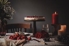 a table topped with a cake covered in frosting and strawberries next to candles