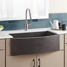 a kitchen sink sitting under a window in front of a counter top with dishes on it