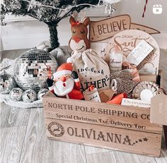 a wooden crate filled with lots of christmas items next to a small tree and ornaments