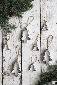 christmas tree ornaments hanging from the side of a wooden wall with pine cones and twine