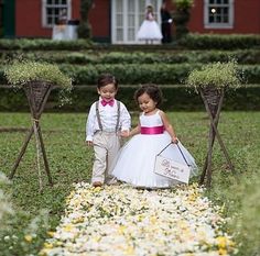 two young children dressed in formal wear walking through flowers