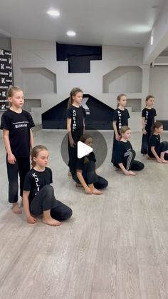 a group of young children standing around each other in front of a black object on a wooden floor