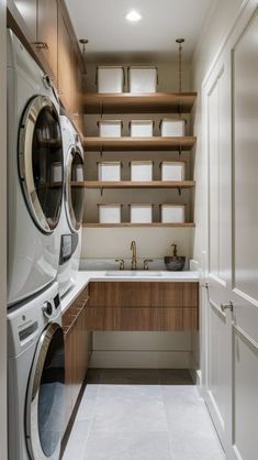 a washer and dryer in a laundry room with wooden shelves on the wall