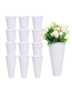 a bunch of white cups with flowers in them