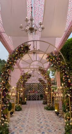 an archway decorated with flowers and greenery for a wedding or reception in the evening