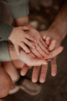 several people holding their hands together in the middle of a circle, with one person's hand on top of the other