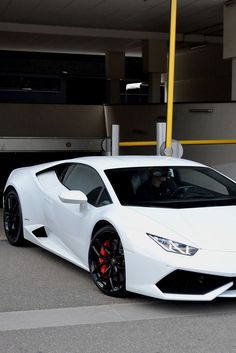 a white sports car parked in front of a parking garage