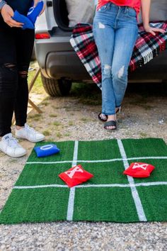 two people standing next to a car with an inflatable frisbee on the ground