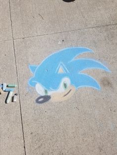 a drawing of sonic the hedgehog is on the sidewalk next to some crayons