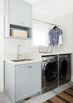 a washer and dryer in a small laundry room with white cabinets on the wall