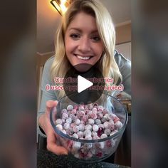 a woman holding a bowl full of candies in front of her face and smiling