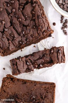 two pieces of chocolate cake sitting on top of paper next to a bowl of chocolate chips