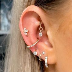 a woman wearing three different types of ear piercings