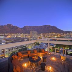 an outdoor seating area with lights on the floor and mountains in the background at night