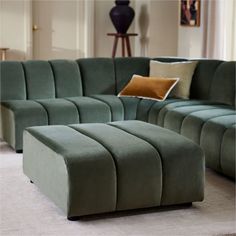 a living room with a green couch and ottoman