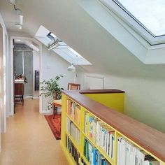 an attic loft with skylights and bookshelves in the hallway, along with a yellow bookcase full of books