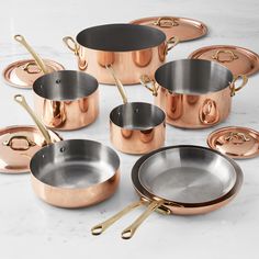 an assortment of pots and pans on a marble countertop with gold handles,