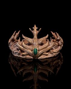 a crown made out of wood with green beads on the sides and leaves around it