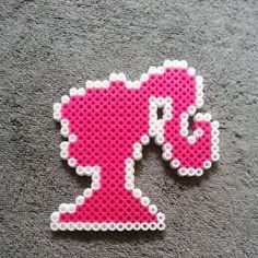 a pink and white beaded brooch with an elephant on it's back