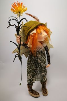 a doll with orange hair holding a flower