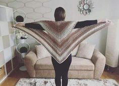 a woman standing in front of a couch with a crocheted shawl over her shoulders