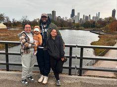 two adults and a child standing in front of a body of water