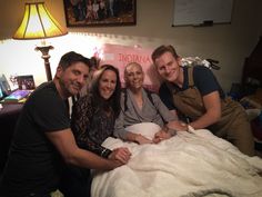 a group of people sitting on top of a bed in a bedroom next to a lamp