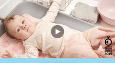 a baby laying in a sink next to a dishwasher with the video below it's caption