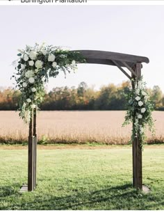 an outdoor wedding ceremony setup with flowers and greenery on the arch, in front of a cornfield