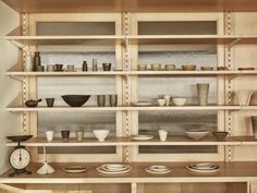 the shelves are filled with bowls, plates and other things on display in front of a clock