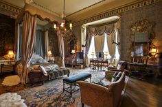 an ornate bedroom with four poster bed, chandelier and two couches in it