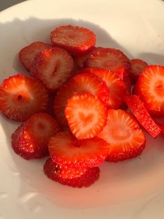 sliced strawberries in a white bowl on a table