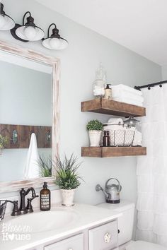 a bathroom with two shelves above the toilet and a mirror on the wall over the sink